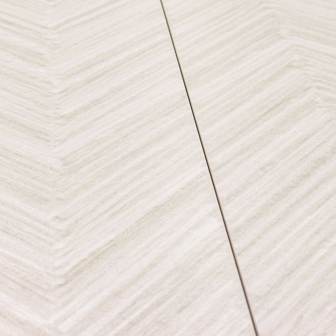 angled close up of the tilesinspired solenne white structured that highlights the chevron pattern and texture. the light shades of grey and white make up a beautiful minimalist pattern tile. 
