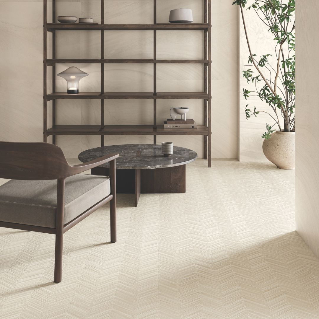 a modern living room iwth dark walnut wood furnishings. the floors are solenne beige structured with the chevron pattern pulling your eyes into the room. the back wall behind the wall shelving is the solenne beige with a grand flowy stone pattern. 