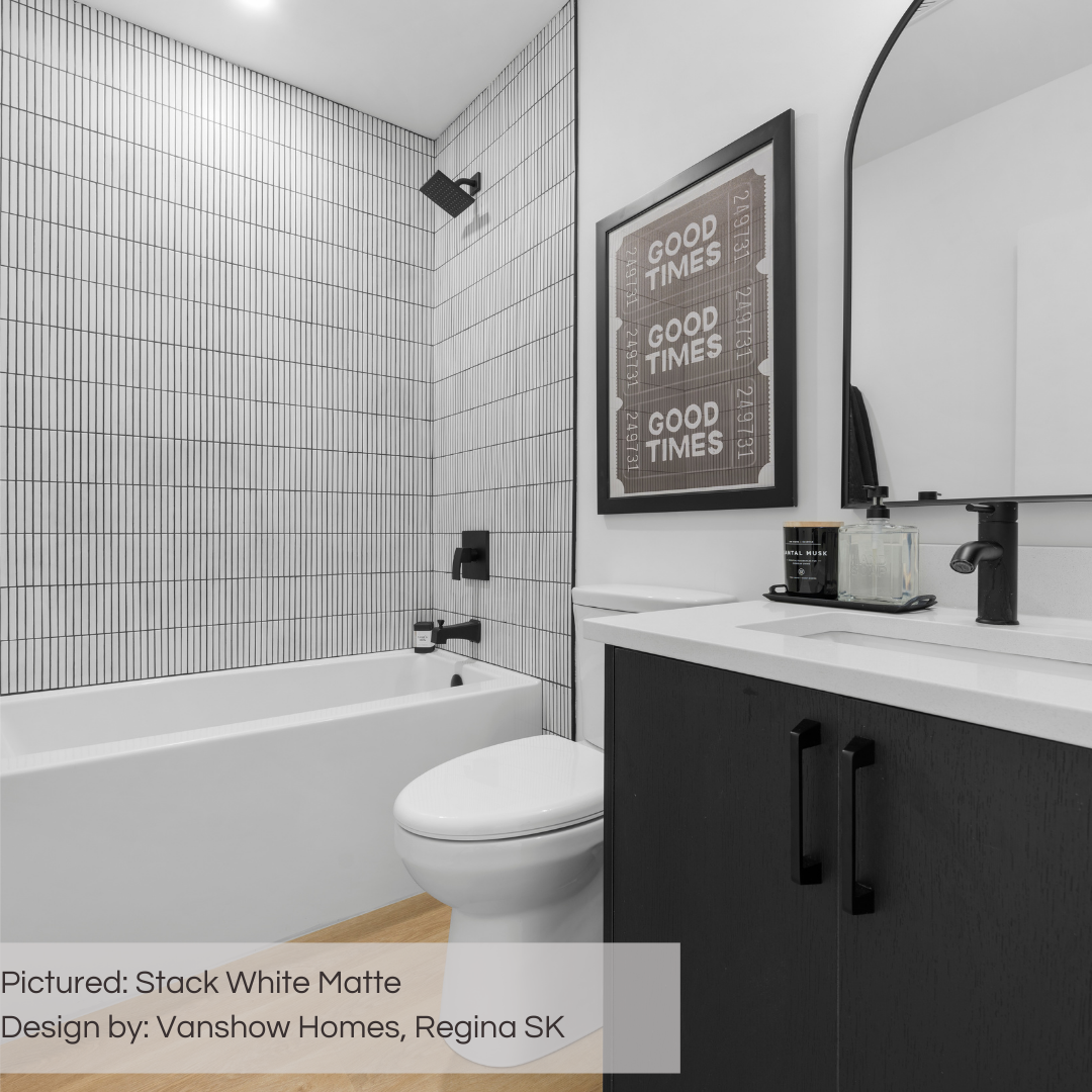 A modern black and white washroom with a black accessories, white walls and oak floors. The shower is tiled with tilesinspired stack white matte kitkat mosaic tiles with dark grout for lots of visual interest! 