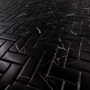 Angled close up of black marquina marble look 1x3 herringbone mosaic sheet tiles to show the deep colour, marble veining and finish. 