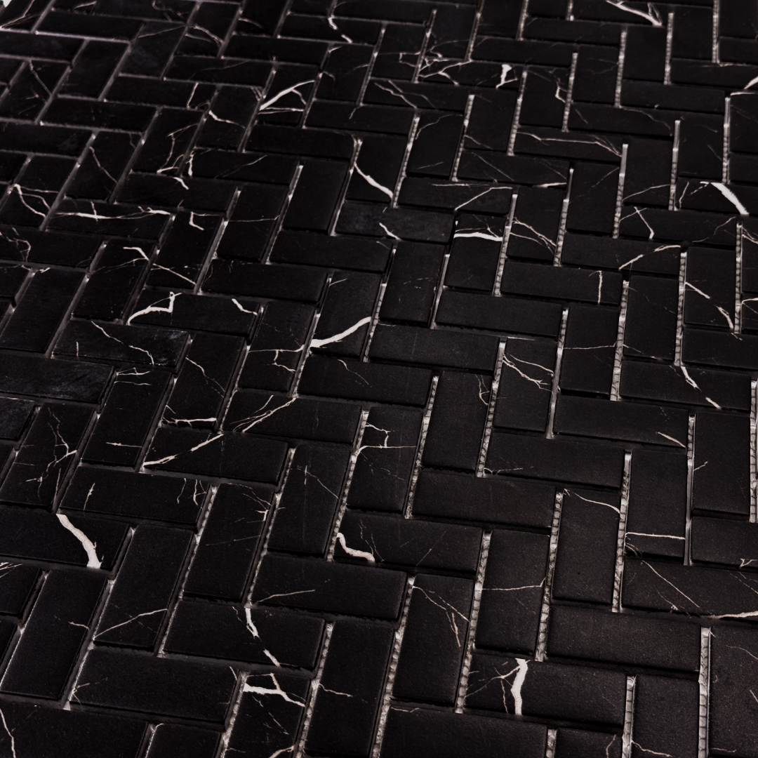 Angled ariel view of black marquina marble look 1x3 herringbone mosaic sheet tiles to show the deep colour, white marble veining and finish. 