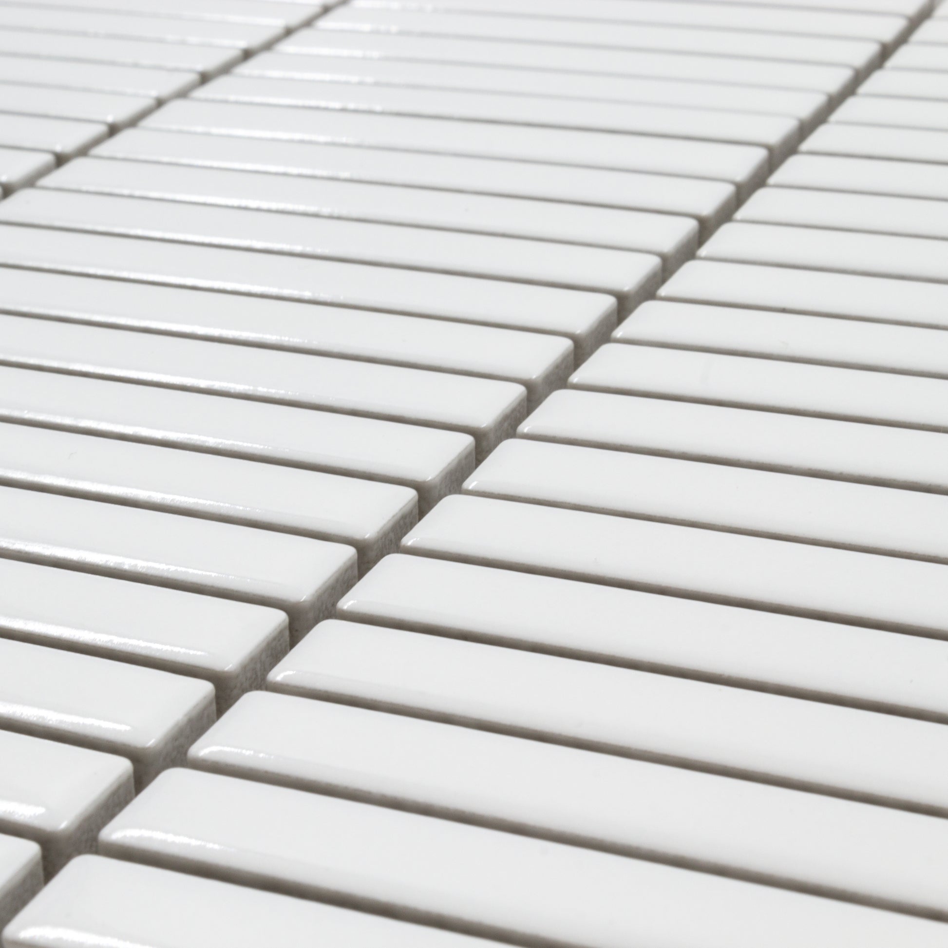 Angled close up view of a single sheet of mini kitkat stacked mosaic tiles in white glossy. The sizing is 3/8' x 3-5/8" per tile, 10.5" X 12" per sheet