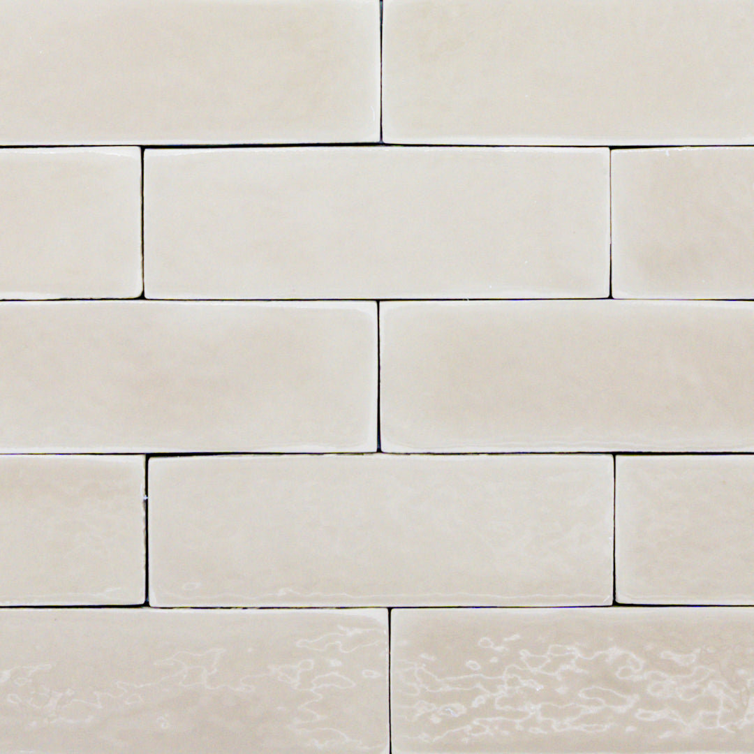 A group of 2x6 glossy beige subway tiles in a brick layout