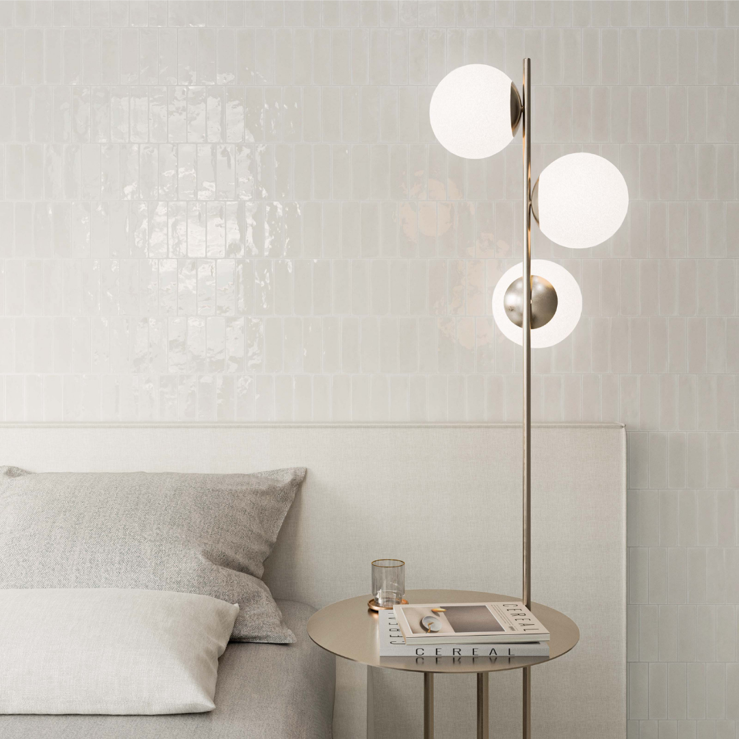A white monochromatic bedroom and the wall behind the bed is a glossy 2x6 white woodland cloud tile. the tiles catch and bounce the light. 