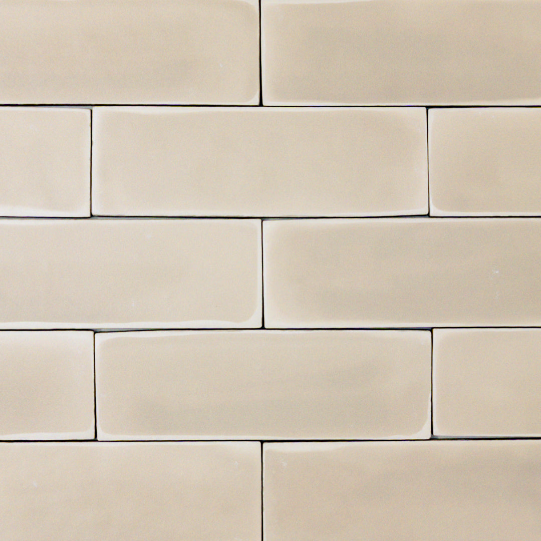 a group of beige 2x6 matte subway tiles with a soft texture and variance in a brick layout. 