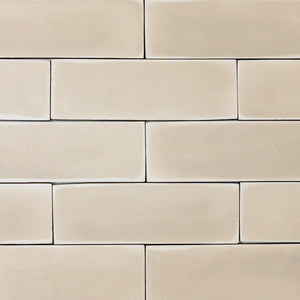 a group of beige 2x6 matte subway tiles with a soft texture and variance in a brick layout. 