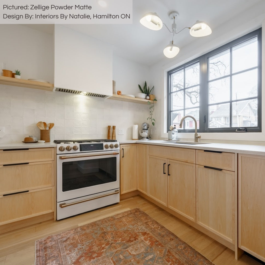 A minimalist modern organic look kitchen with light wood lower cabinets, open shelving and warm toned zellige powder white matte textured handmade look tiles installed on the backsplash. 