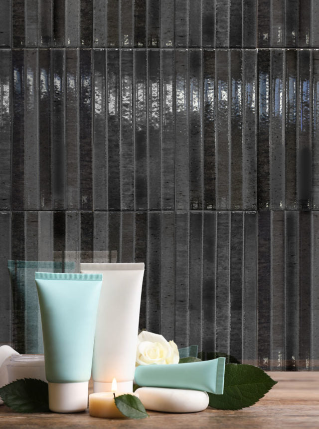 Clsoe up of a tiled bathroom backsplash. The tiles are 5x10 panel tile in glossy black, the tile has a 3D linear faux grout line kitkat look. This installation highlights the colour variation. 