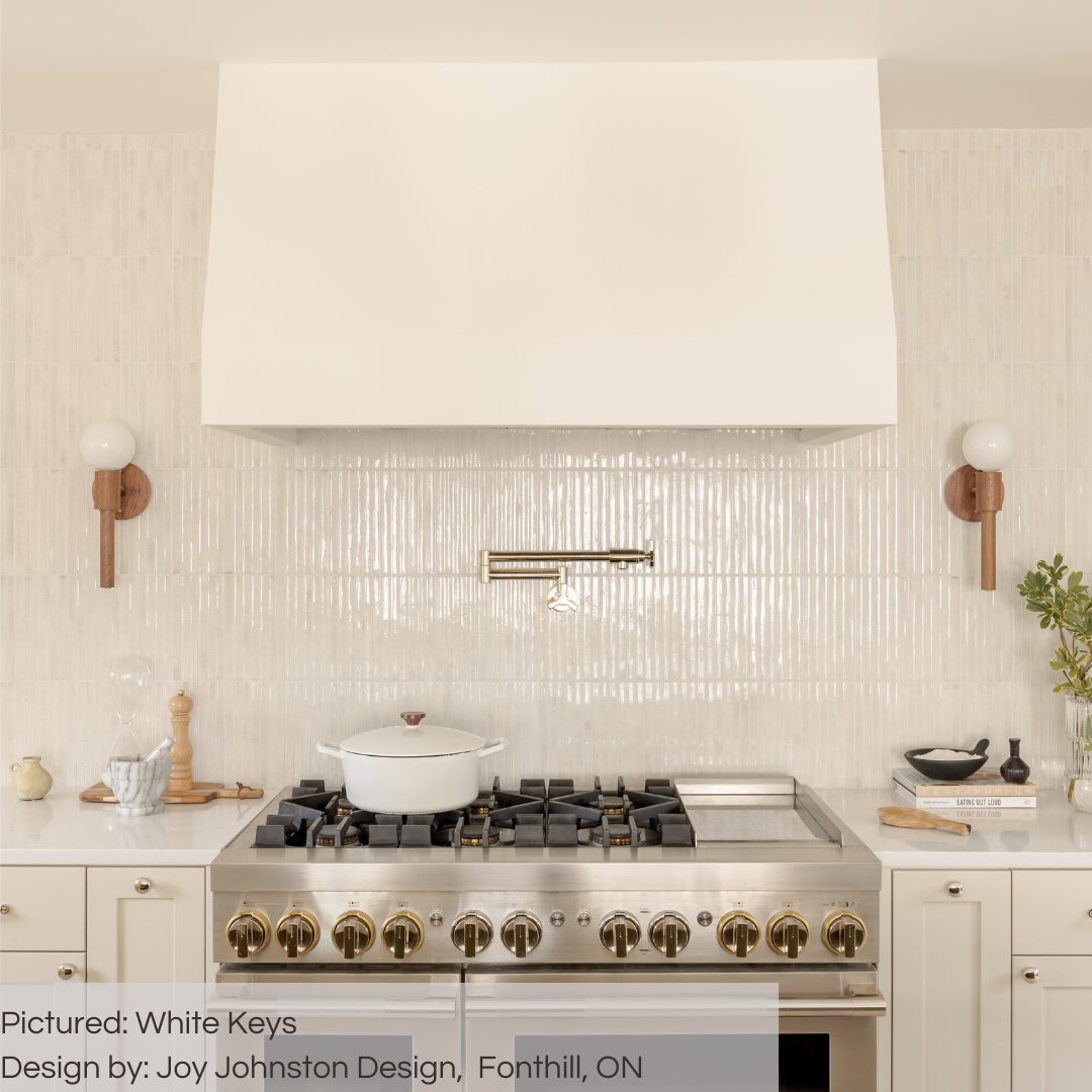 A stove backsplash with a gold pot filler and wood look sconces. The tiles are 5x10 panels in glossy milk white, the tile has a 3D linear faux grout line kitkat look and colour variation. 