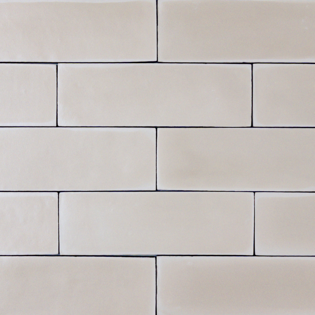 a group of taupe 2x6 matte subway tiles with a soft texture and variance in a brick layout. 