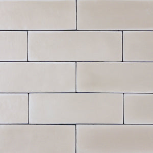 a group of taupe 2x6 matte subway tiles with a soft texture and variance in a brick layout. 