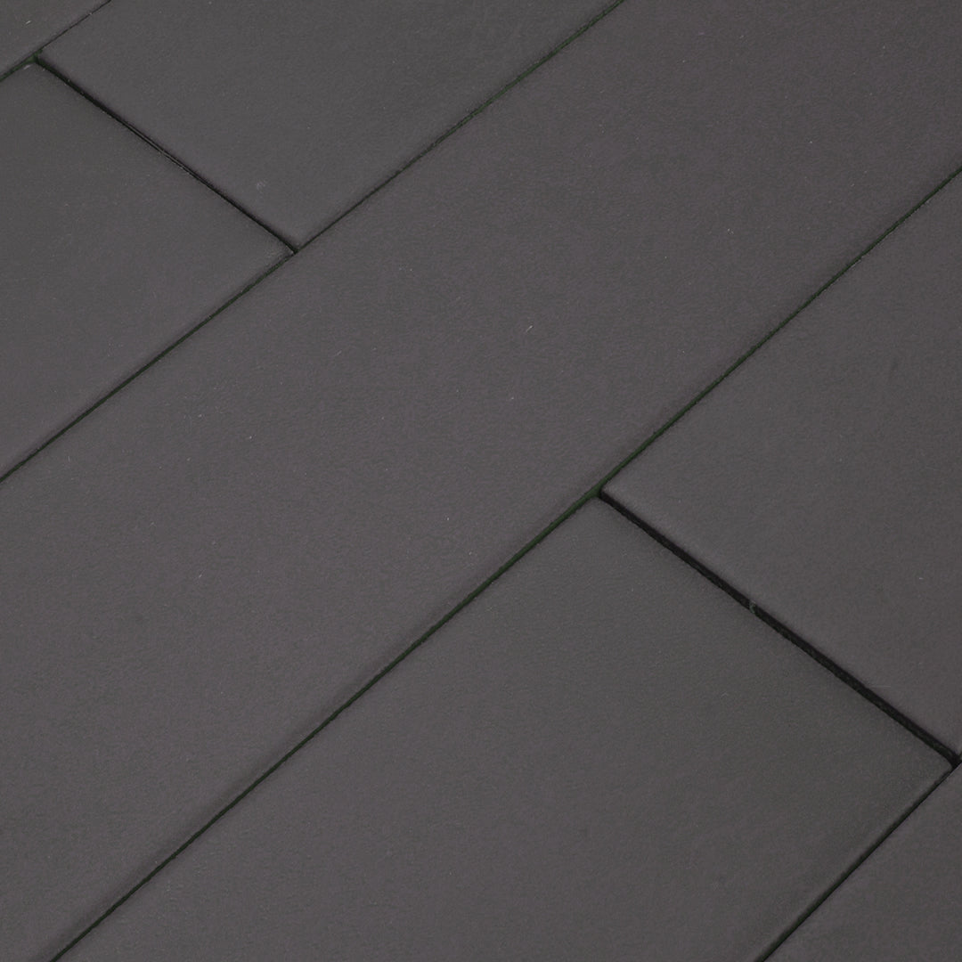 Ariel close up view of a group of charcoal black 17.5" X 3.25" plank look tiles with subtle texture and pattern for floors or walls laid out in a brick layout. 