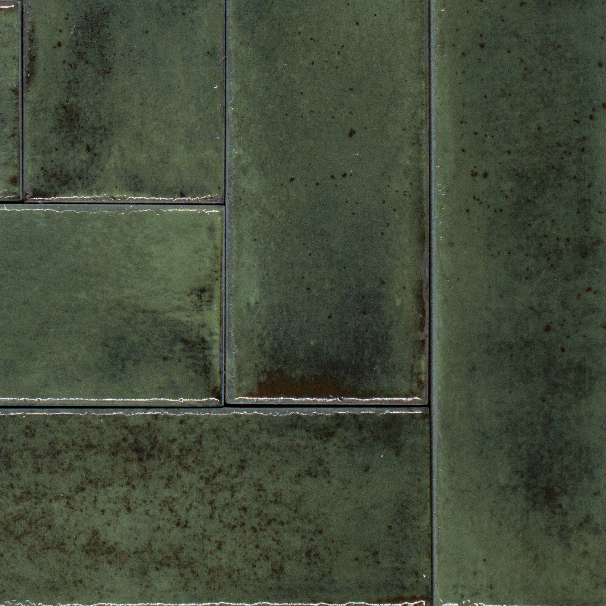 A close up of a group of Matisse Green tiles, the glossy finish and handpainted speckled look are displayed. 
