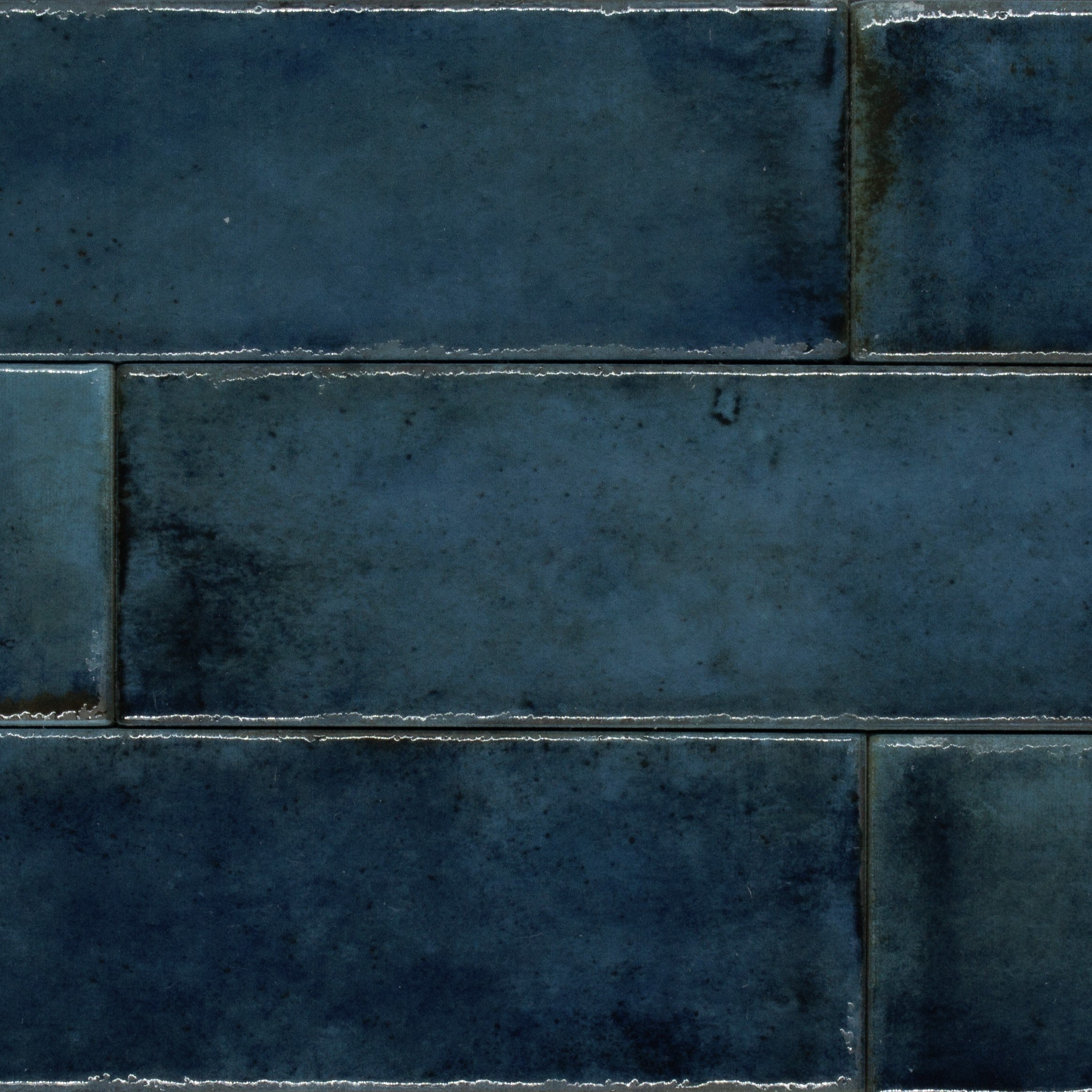 A close up of a group of mattise blue glossy tiles where the edges look worn and natural looking. 