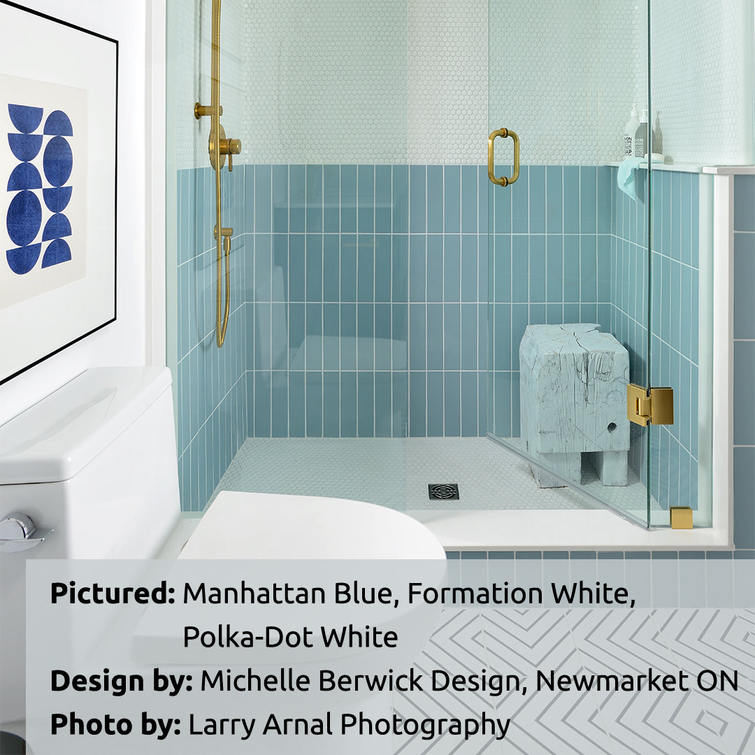 A fun and pretty shower with blue stacked tiles on the lower half of the walls in the shower. The floors and upper half of the walls in the shower are polka dot penny round white tiles 