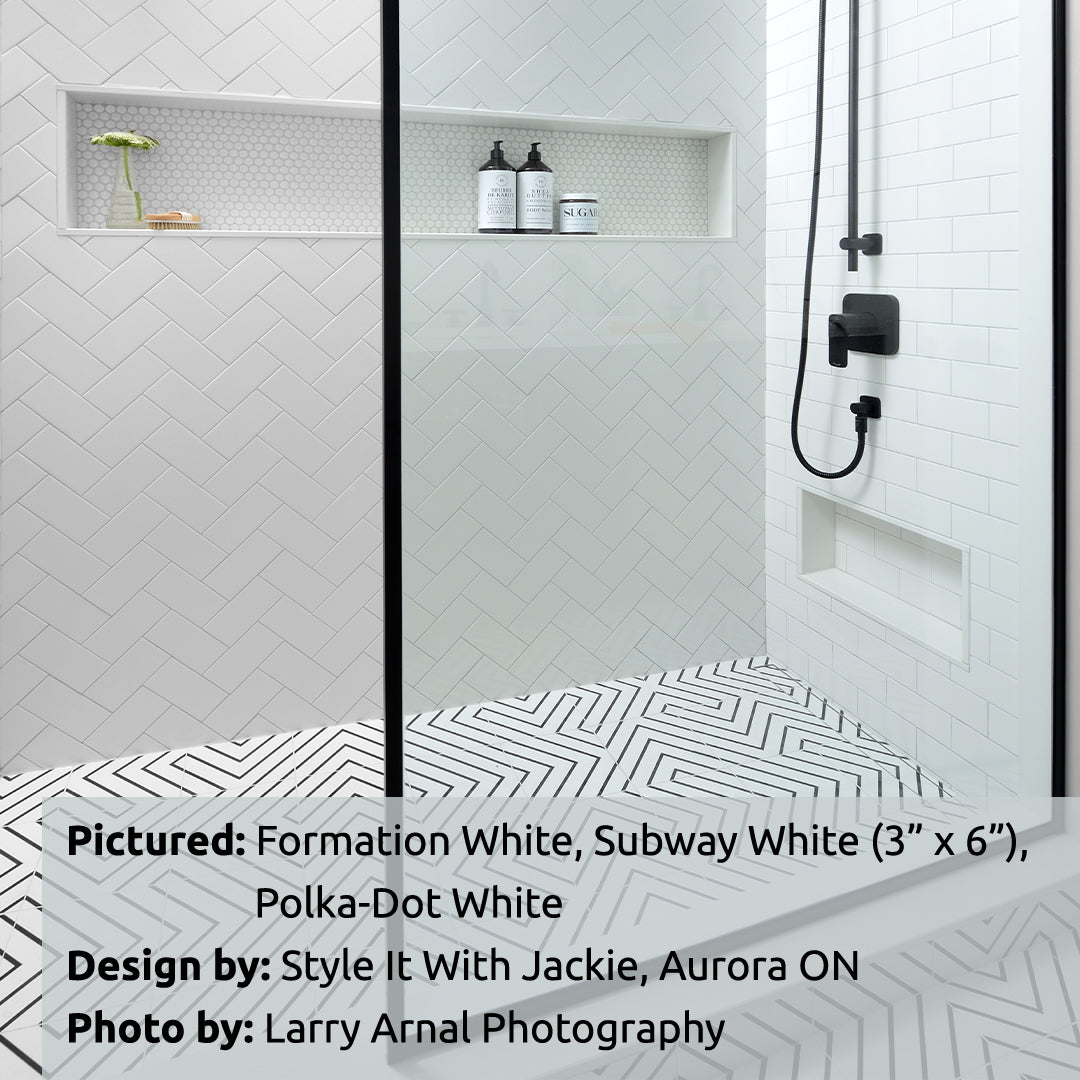 A large walk in shower with 3x6 glossy white subway tile installed in a herringbone pattern on the shower walls, polka dot penny white tiles on the back of the niche. the two tiles sizes compliment each other. 